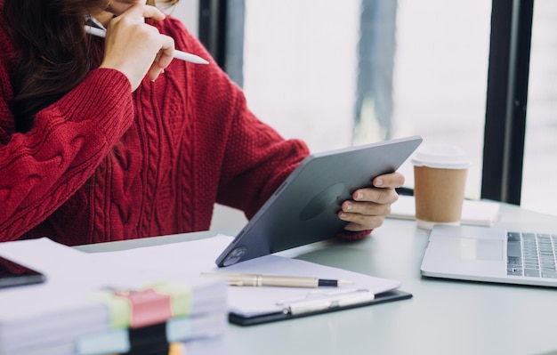 Young business woman sitting in office at table and using smartphone On desk is laptop and tablet computer on screen charts and graphs Woman analyzing data Student learning online