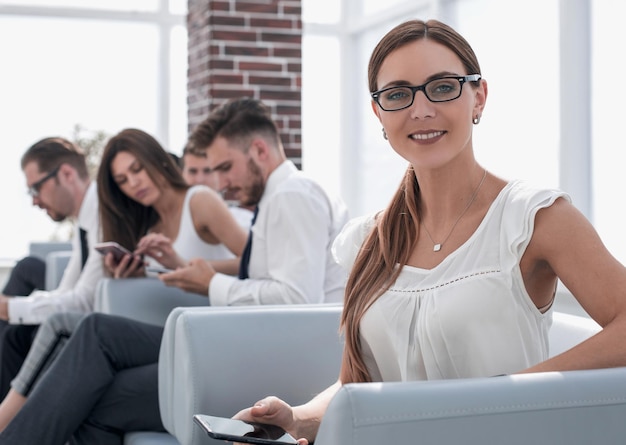 Young business woman sitting in office waiting roompeople and technology