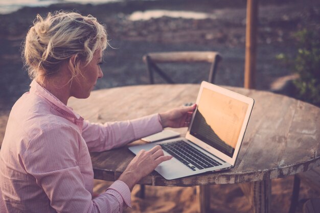 Foto giovane donna d'affari seduta all'aperto e lavora con il laptop - connessione internet wireless gratuita per ufficio e stile di vita alternativi - workstation nomade digitale freelance ovunque