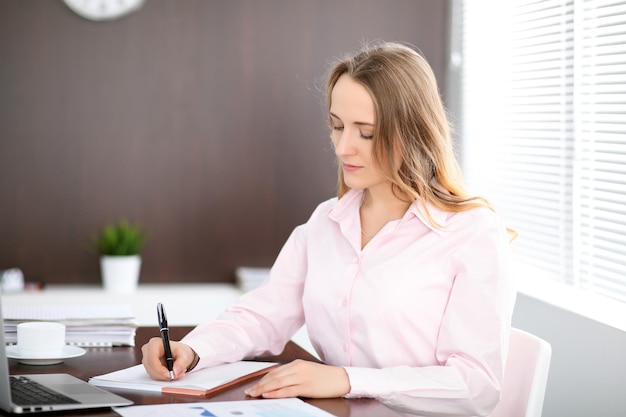 Young business woman sitting at the table in the office