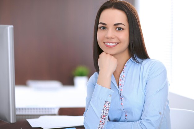 Young business woman sitting and writing at the table  in office