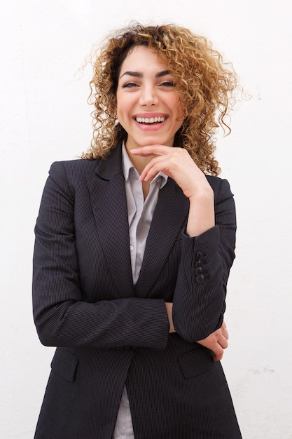 Young business woman smiling against white wall