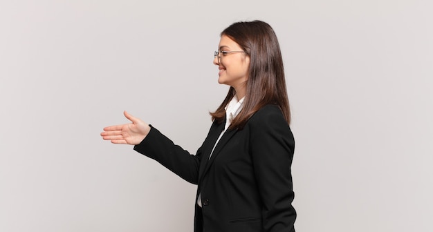 Giovane donna d'affari che sorride, ti saluta e ti offre una stretta di mano per concludere un affare di successo, concetto di cooperazione