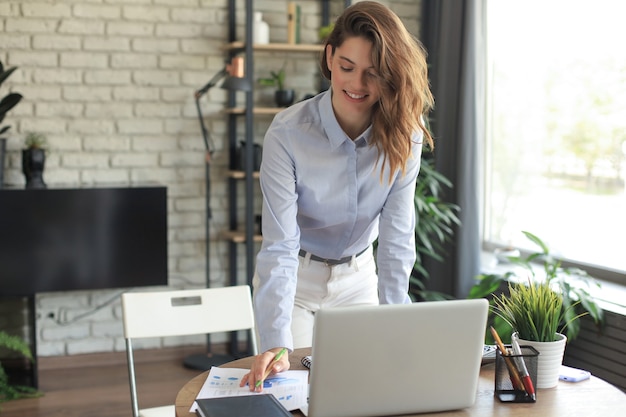 Young business woman standing in her home office reading notes.