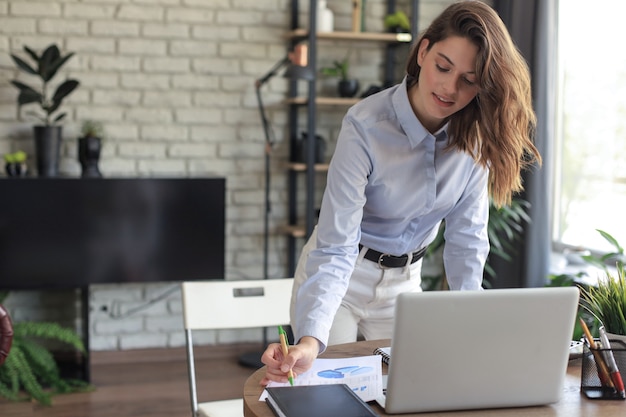 Young business woman standing in her home office writing notes.