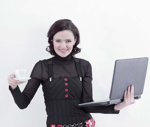 Молодая деловая женщина, стоящая с чашкой кофе и ноутбуком