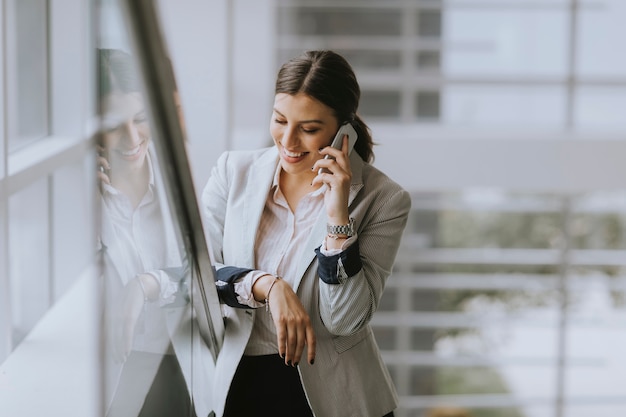 Young business woman stands on the stairs at the office and use mobile phone