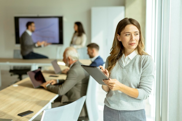 Young business woman at startup office with digital tablet in front of her colleagues as team leader