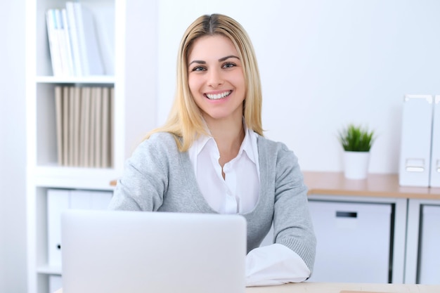 Young business woman or student girl sitting at office workplace with laptop computer. Home business concept.