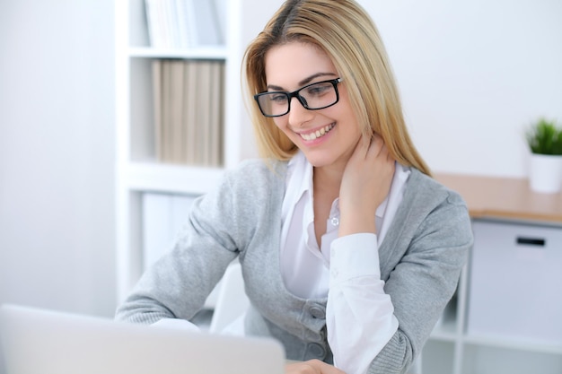 Young business woman or student girl sitting at office workplace with laptop computer. Home business concept.