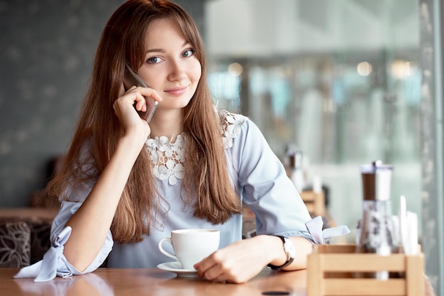 コーヒーショップに電話で話している若いビジネス女性