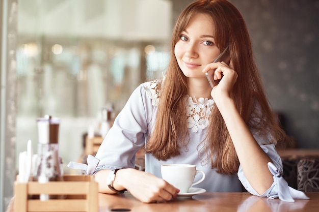 コーヒーショップに電話で話している若いビジネス女性