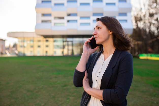 Young business woman talking on the phone on the street near the office center