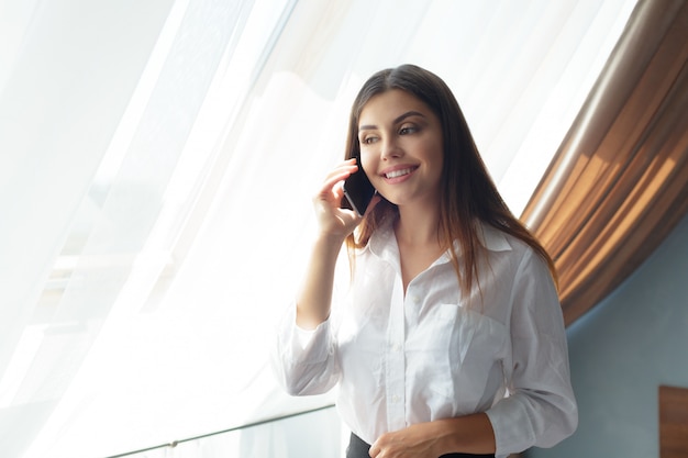 Young business woman talking with phone in the hotel.