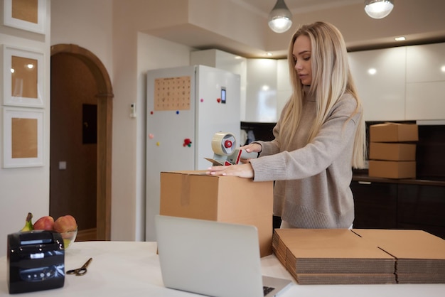 Young business woman taping up a cardboard box in the office\
relocation and new business concept