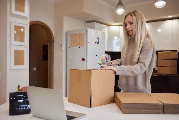 Молодая деловая женщина заклеивает картонную коробку при переезде в офис и новой бизнес-концепции