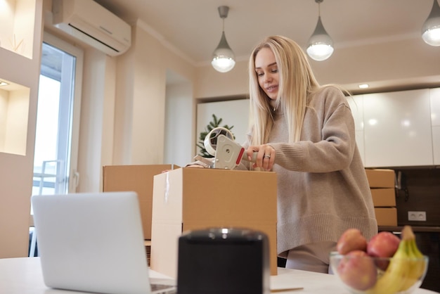 Young business woman taping up a cardboard box in the office relocation and new business concept