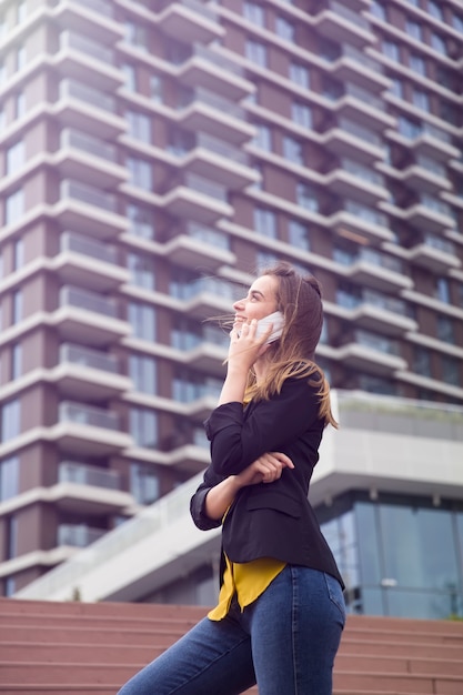 La giovane donna di affari usa il cellulare alla via