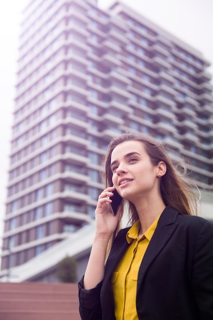 若いビジネス女性が路上で携帯電話を使用します。