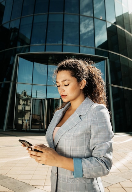 La giovane donna d'affari utilizza un telefono cellulare davanti a un moderno centro affari