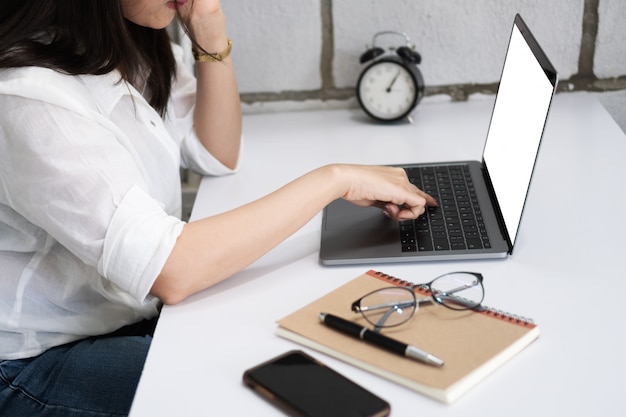 写真 空のデスクトップ画面で作業するためにラップトップコンピュータを使用している若いビジネスの女性。