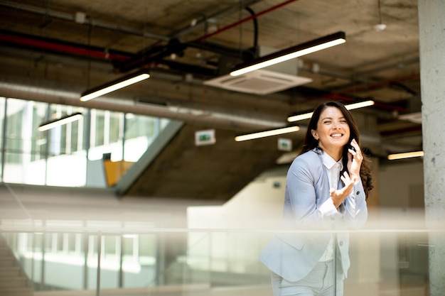 Young business woman using mobile phone in the office hallway