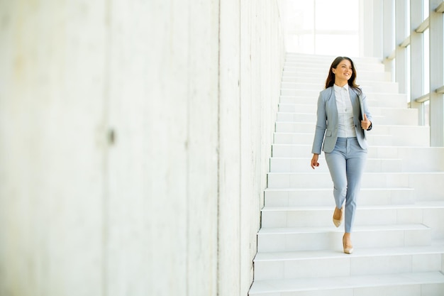 Young business woman walking down the stairs and holding laptop