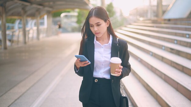 Una giovane donna d'affari che indossa un abito nero sta usando smart phone