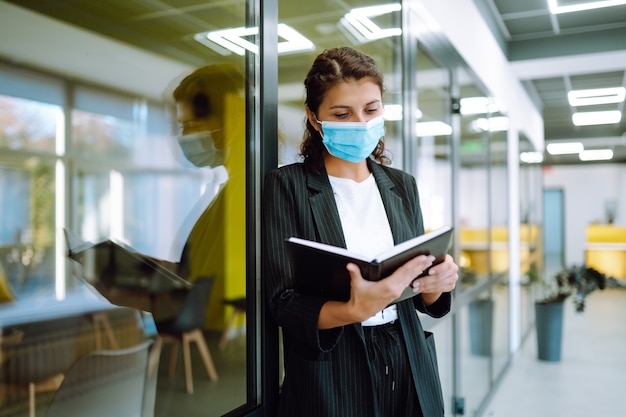 Young business woman wearing a face mask protect from infection of Covid19 standing at office