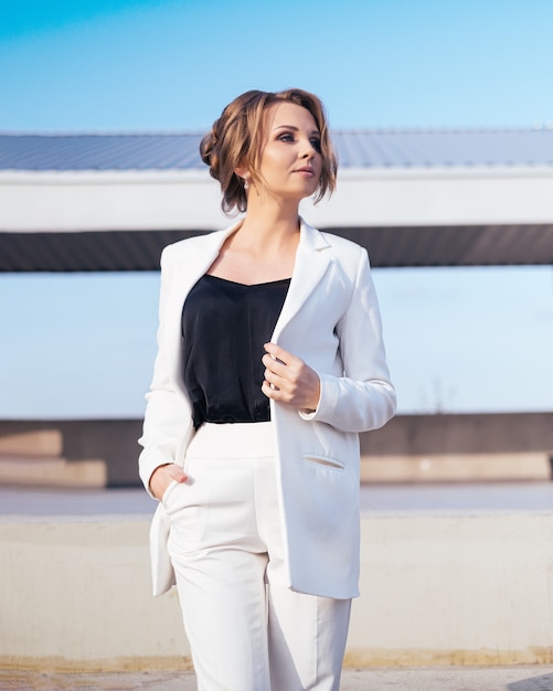 Young business woman in white pantsuit