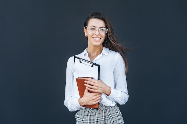 Young business woman with coffee and notebook on grey background.