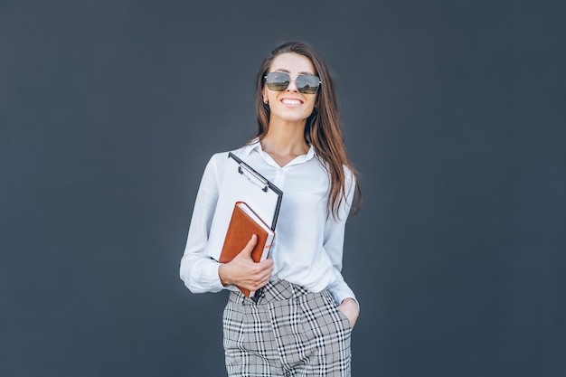 Young business woman with coffee and notebook on grey background