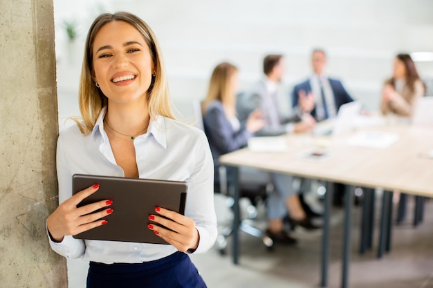 Young business woman with digital tablet in the office hallway