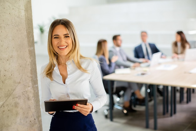 Young business woman with digital tablet in the office hallway