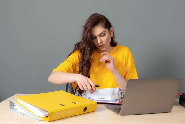 Young business woman with long dark hair working with document in office isolated on gray background