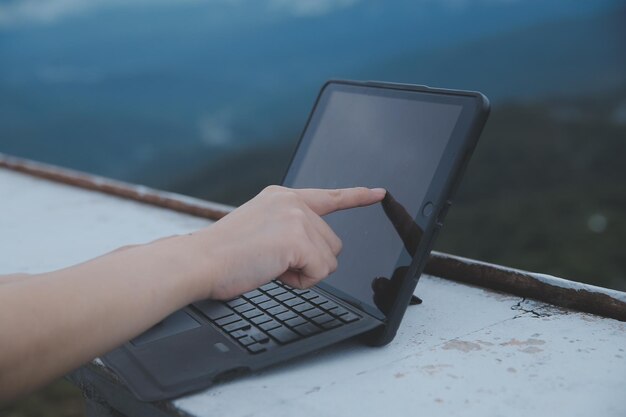 Young business woman working at the computer in cafe on the rock Young girl downshifter working at a laptop at sunset or sunrise on the top of the mountain to the sea working day