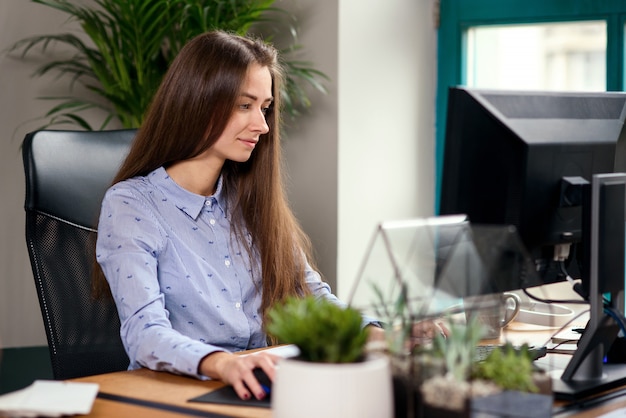 Young business woman working at computer in modern office.