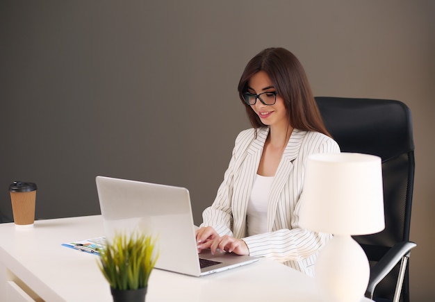 Молодая деловая женщина, работающая в своем офисе с помощью ноутбука.