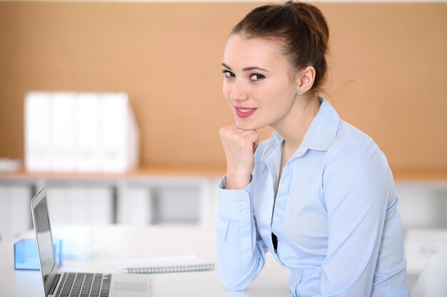 Young business woman working on laptop in office. Successful business concept.