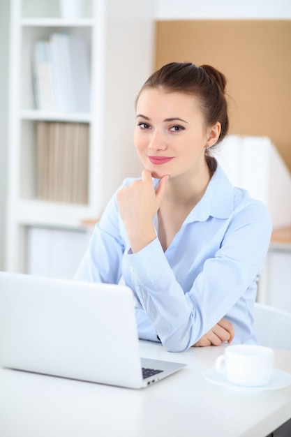 Young business woman working on laptop in office. Successful business concept.