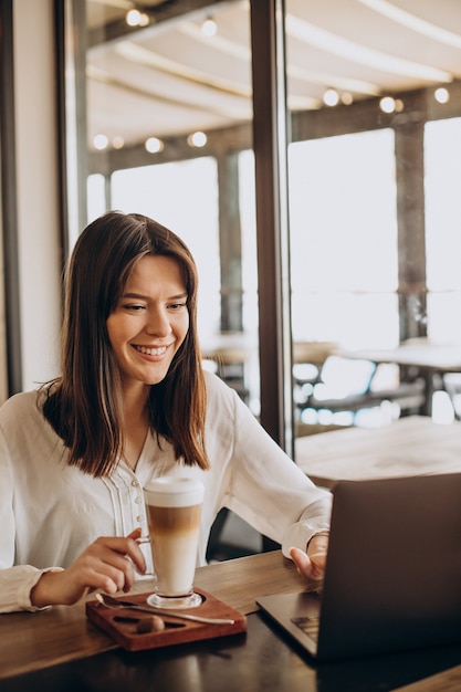 Young business woman working online in a cafe and drinking coffee