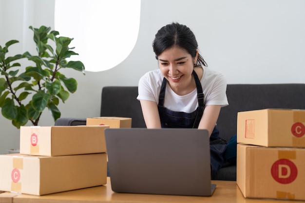 Young business woman working online ecommerce shopping at her shop Young woman seller prepare parcel box of product for deliver to customer Online selling ecommerce