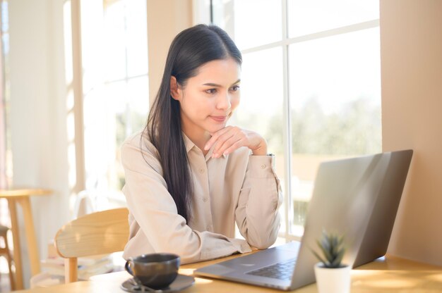 コーヒーショップで彼女のラップトップで働いている若いビジネスウーマン