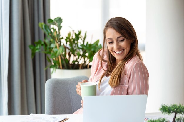 オフィスでコーヒーを飲み窓から眺める若いビジネス女性