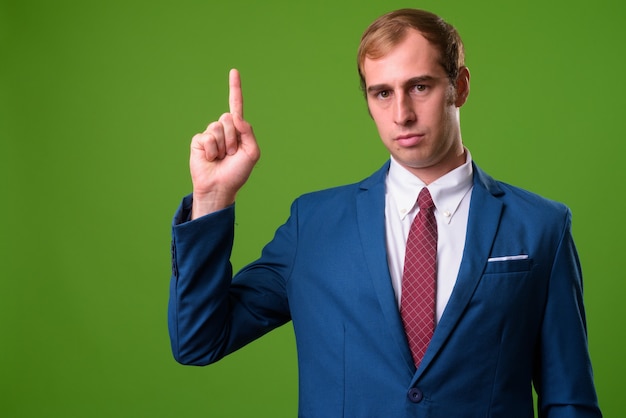 Young businessman against green wall