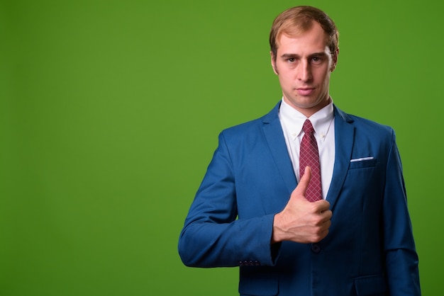 Young businessman against green wall