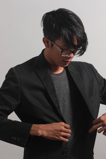 A young businessman in a black shirt, black tie and black suit looks at the camera