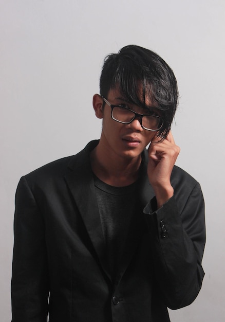 A young businessman in a black shirt, black tie and black suit looks at the camera