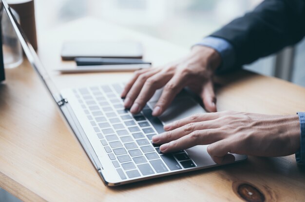 A young businessman in a black suit is working on a laptop from a private residence, working online to reduce the risk of virus infection.