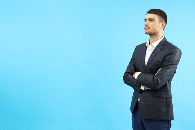 Young businessman on blue background, space for text.